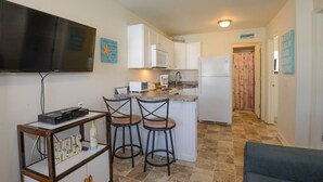 A compact kitchen with a flat-screen TV, a microwave, and a refrigerator. There are two bar stools and a small table with a bottle and a remote control. - AUGUST 8 TO 11 AVAILABLE ...  FAMILIES/COUPLES ONLY  
CUTE UNIT WITH POOL (Seaside Heights)