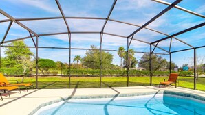 A covered swimming pool with a clear view of the surrounding greenery and a clear sky. - Providence at Rosemont Woods by Florida Star Vacations (Davenport)