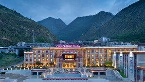 A hotel with a prominent sign reading "CROWNE PLAZA" in front of a mountainous backdrop. - Crowne Plaza Yading by IHG (Garze)