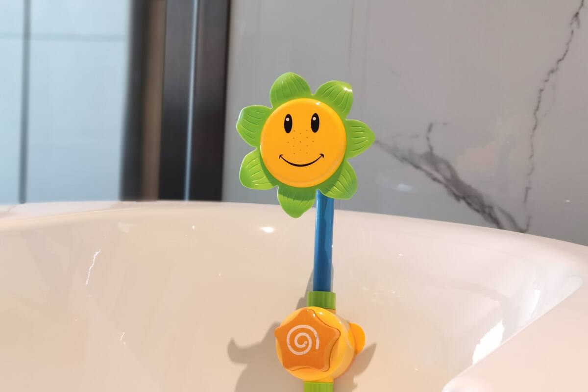 Un lavabo de salle de bain avec un distributeur de savon en forme de fleur et un porte-brosse à dents bleu.