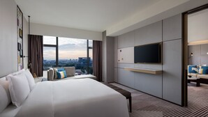 Une chambre d’hôtel moderne dotée d’un grand lit, d’une télévision à écran plat, d’un canapé et offrant une vue sur la ville.