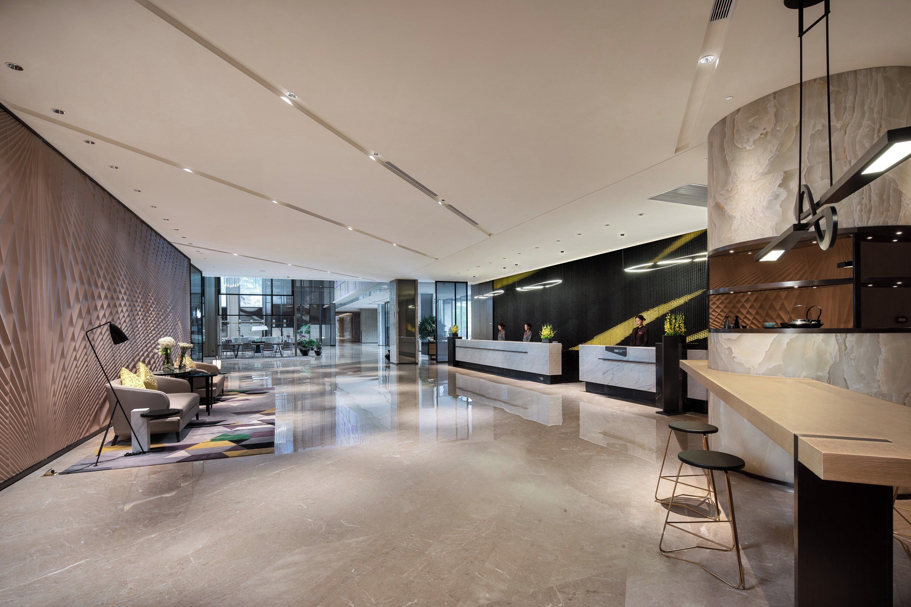 A modern lobby with a reception desk, seating area, and a kitchen counter.