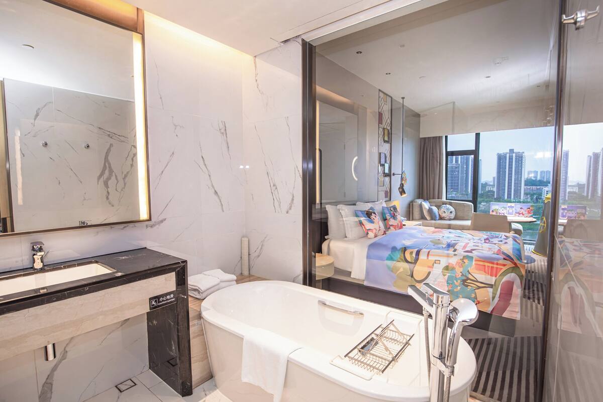 Une salle de bain moderne avec un grand miroir, une baignoire et un lavabo.