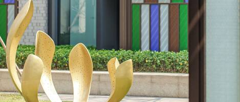 A modern building with a glass facade and a landscaped area with a sculpture.