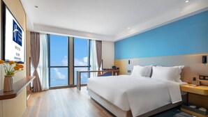 A modern hotel room with a large bed, a desk, and a view of the sky through large windows. - Holiday Inn Express Changsha Shengfu by IHG (Changsha)