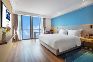 A modern hotel room with a large bed, a desk, and a view of the sky through large windows. - Holiday Inn Express Changsha Shengfu by IHG (Changsha)