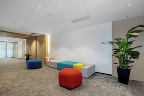 Un espace d’attente moderne, doté d’un canapé, de poufs et d’une plante en pot.