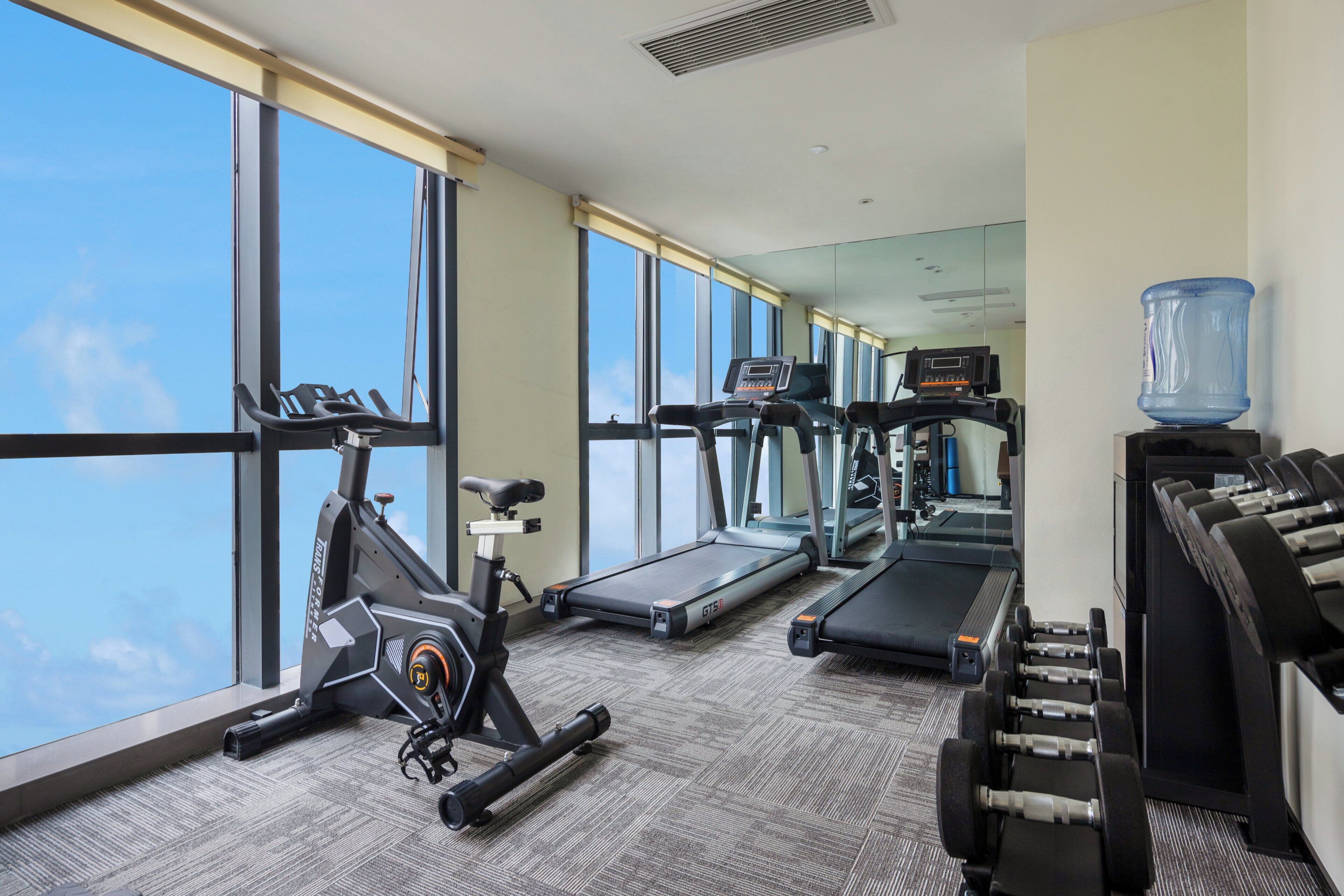 A gym with treadmills, an elliptical, and dumbbells.