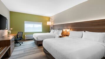 A hotel room with two beds, a desk, a chair, a TV, and a window with a view.