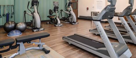 A fitness center with treadmills, elliptical machines, and exercise balls.