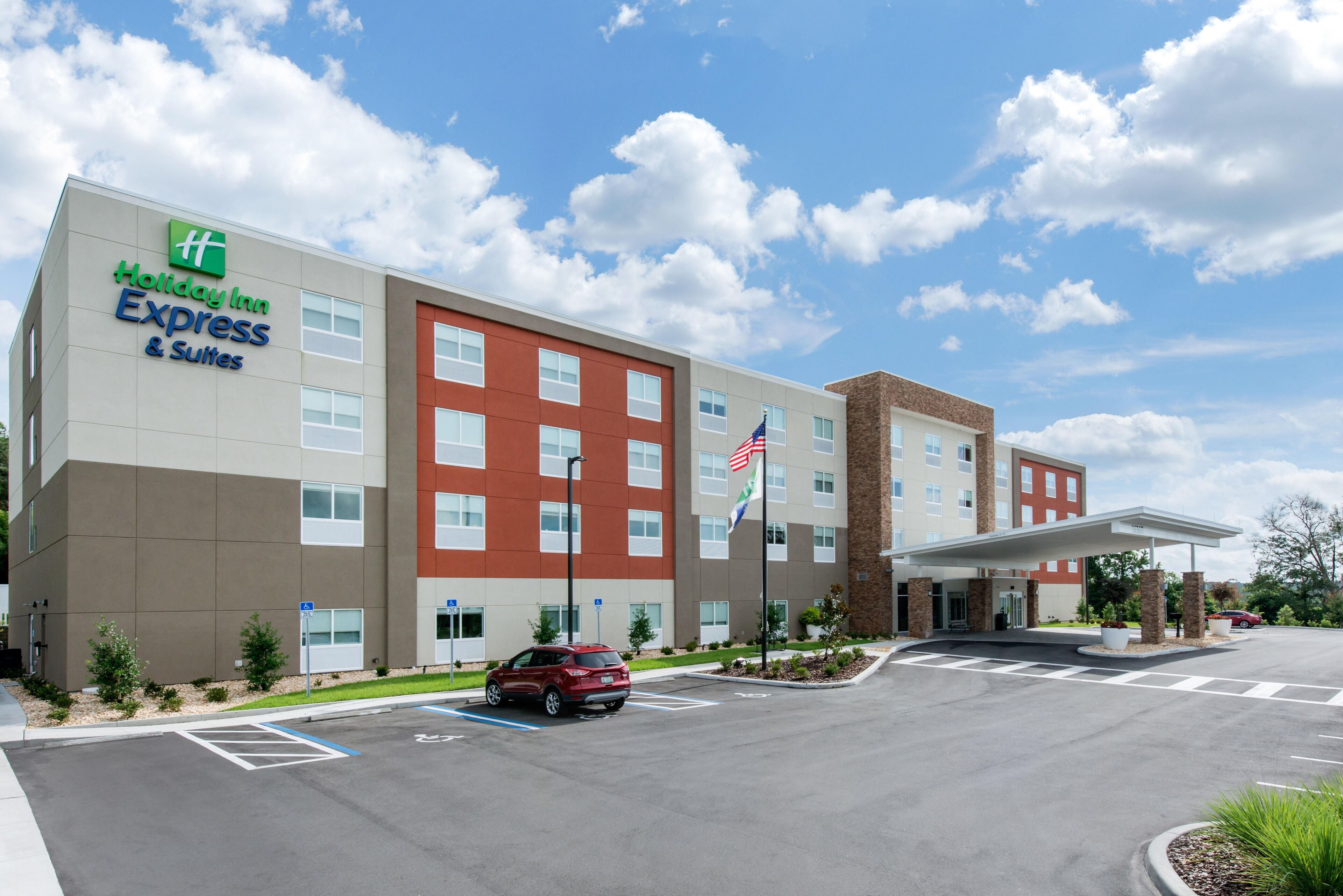 A Holiday Inn Express building with a parking lot, a red car, and a clear sky.