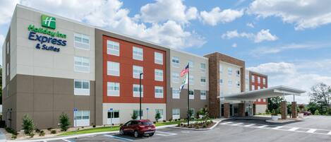 A Holiday Inn Express building with a parking lot, a red car, and a clear sky.