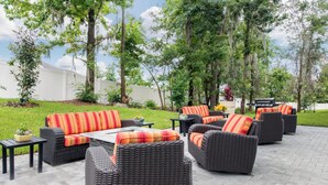An outdoor patio area with wicker furniture, a dining table, and a barbecue grill.