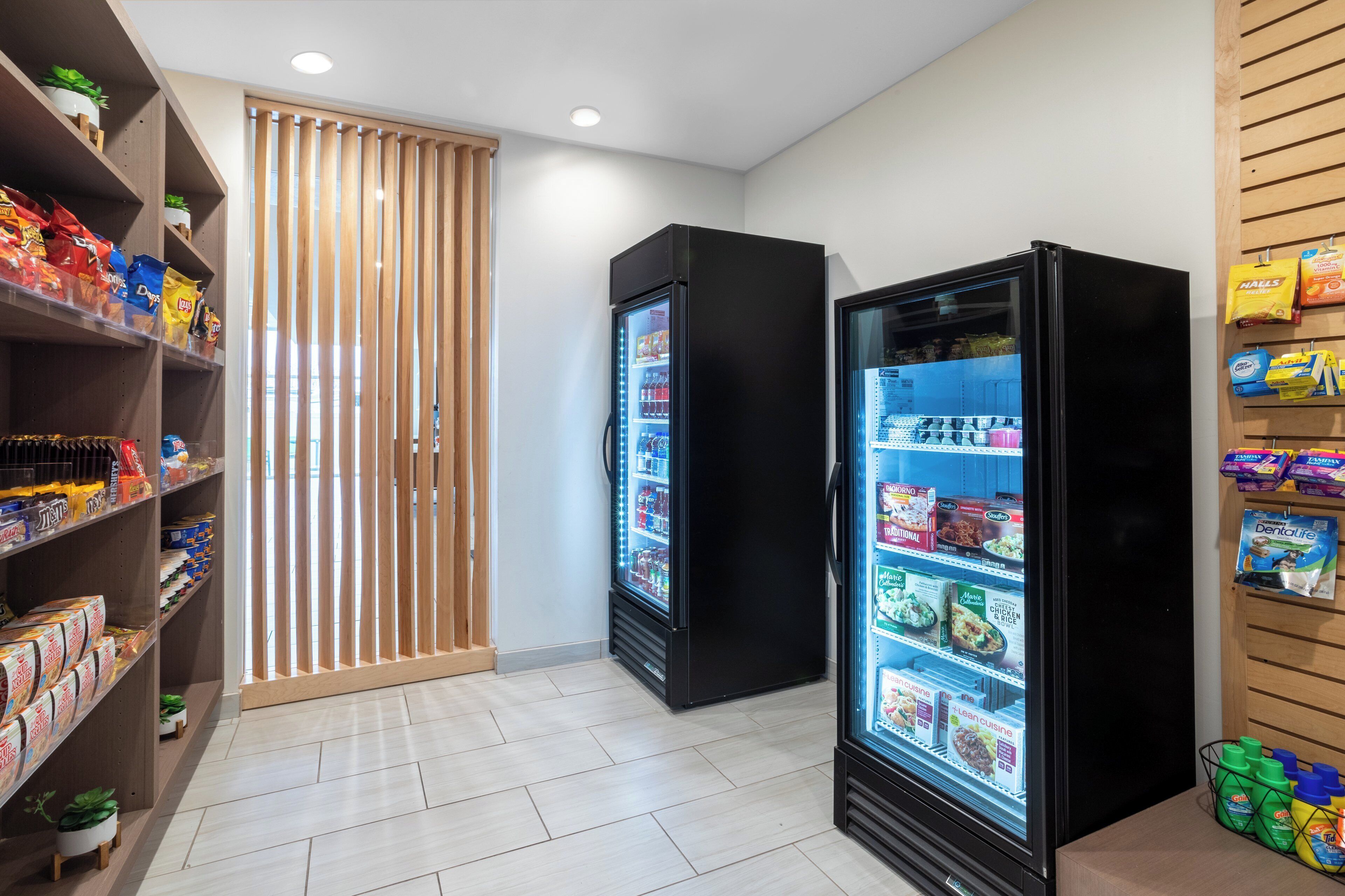 A clean, modern retail space with two refrigerated display cases and shelves stocked with snacks and beverages.