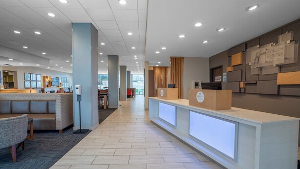 A modern hotel reception area with a reception desk, seating area, and a view of the lobby.