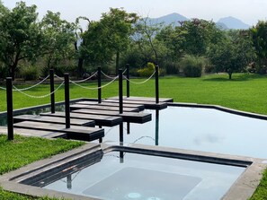 Alberca al aire libre, sombrillas en la alberca y camastros