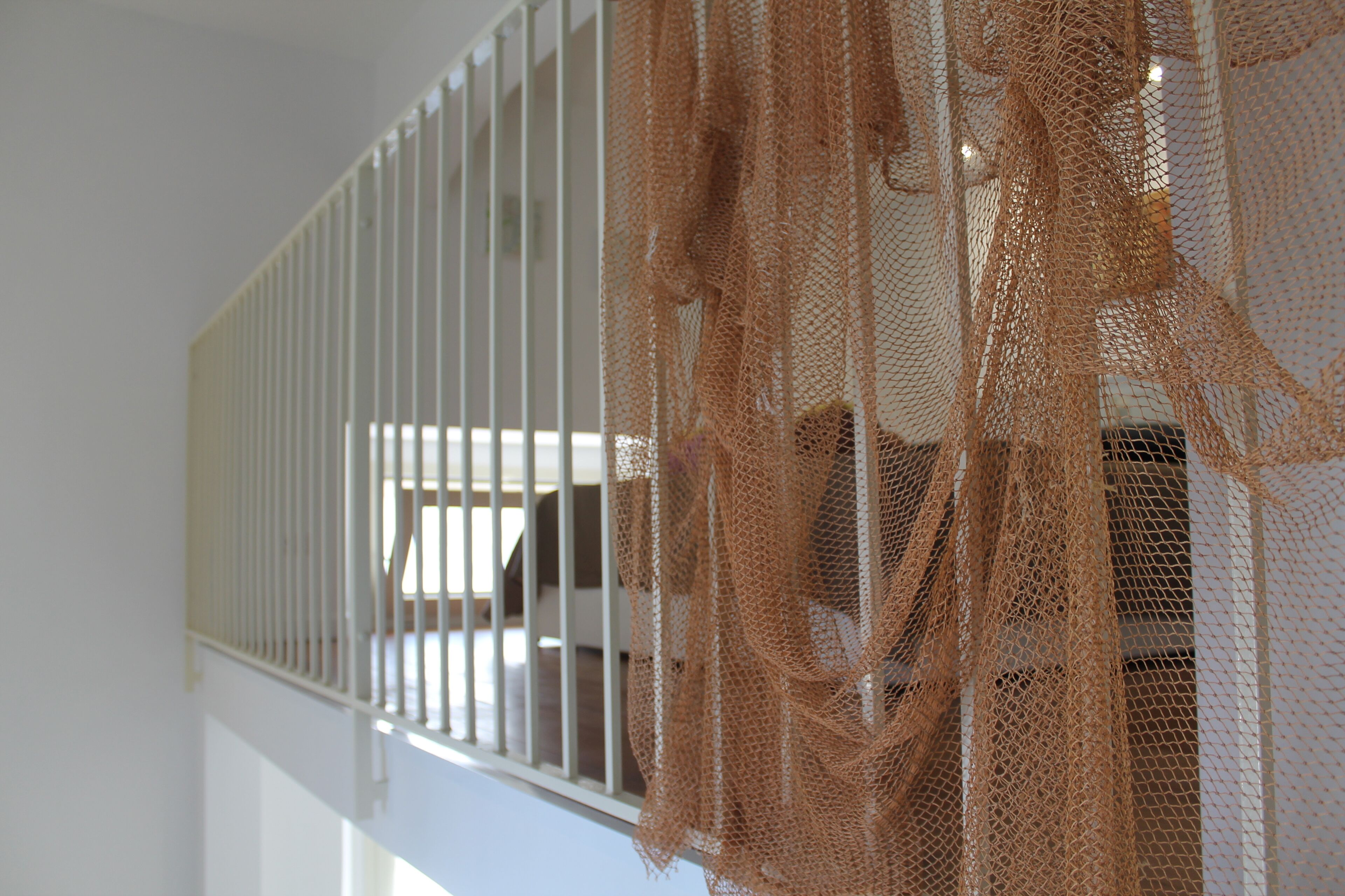 A white railing with a netted barrier.