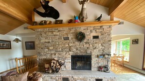 Una sala de estar acogedora con chimenea de piedra, techo de madera y un espacio de descanso confortable.
