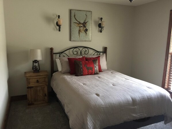 Un dormitorio con cama, mesita de noche, lámpara de pared y un cuadro enmarcado.