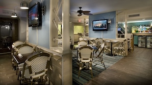 A bar area with wicker chairs, a bar counter, and a television mounted on the wall. - Gorgeous Ocean View Modern 2 Bedroom Condo w/ Access to Resort Amenities (Myrtle Beach)