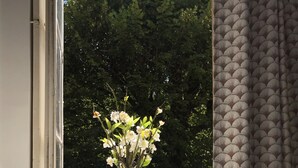Un jarrón blanco con flores sobre una mesa junto a una ventana.