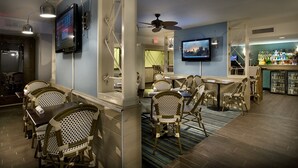 A bar area with wicker chairs, a bar counter, and a television mounted on the wall.