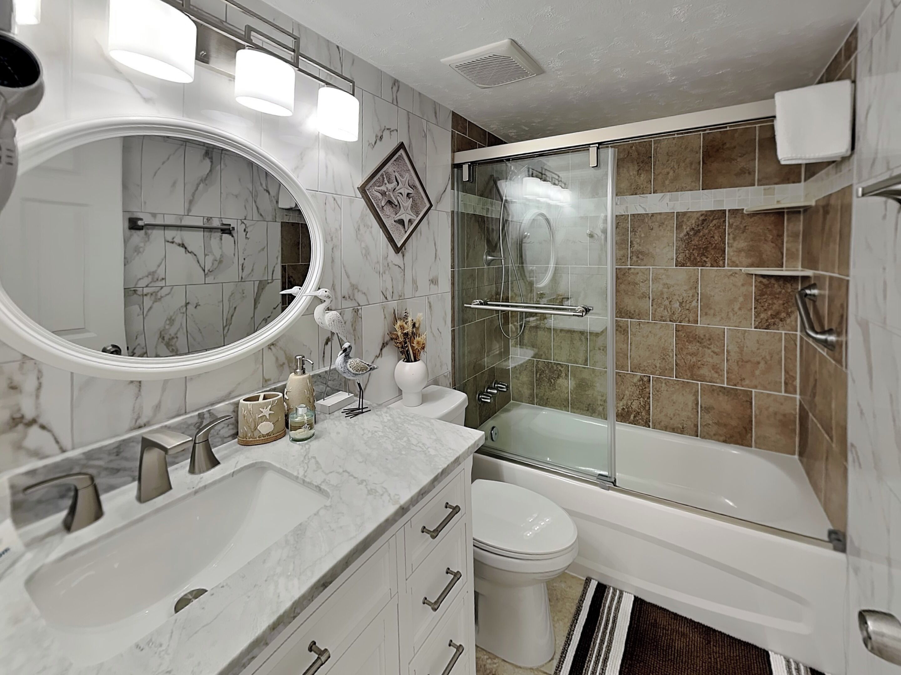 A bathroom with a marble vanity, a glass-enclosed shower, and a toilet.
