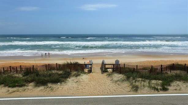 A beach with a wooden fence and a sign, leading to the ocean. - OCEAN VIEW CONDO w/ Pool, Cable, Wifi, BEACH ACCESS. Ormond-by-the-Sea  (Ormond Beach)