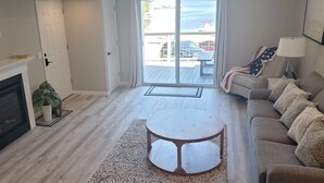 Un salon avec une cheminée, un canapé, une table basse et une vue sur l’extérieur.