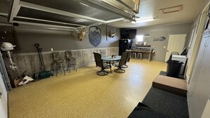 A garage with a dining table and chairs, a mounted deer head, and a 'Welcome' sign. - 40 Creek Lodge South at Waubay Lake (Grenville)