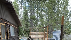 Une terrasse en bois avec des sièges d’extérieur, un barbecue et une poubelle.