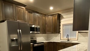 A modern kitchen with stainless steel appliances, wooden cabinets, and a granite countertop.