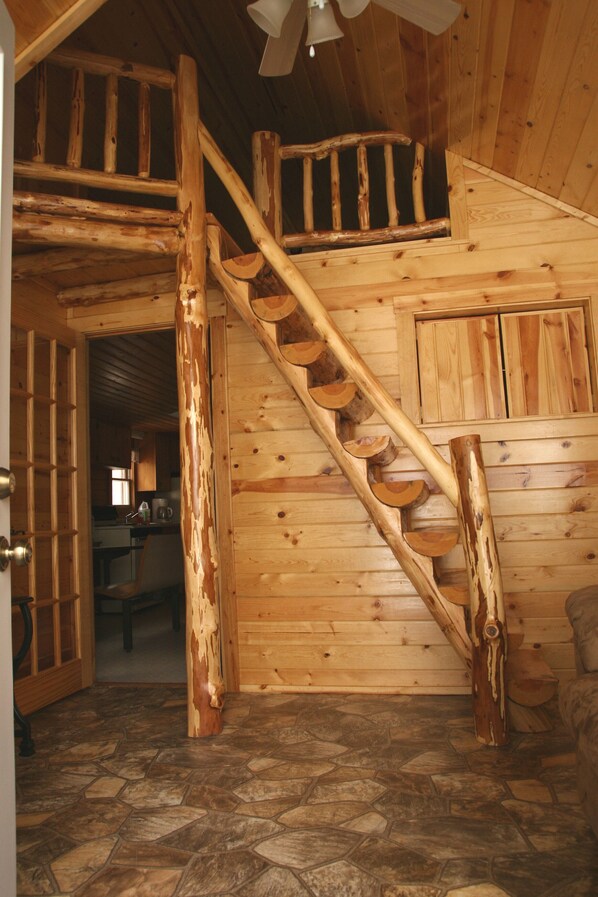 A wooden staircase with a rustic design, leading to a loft area. - Chief Lake Lodge Cabin #2 (Hayward)