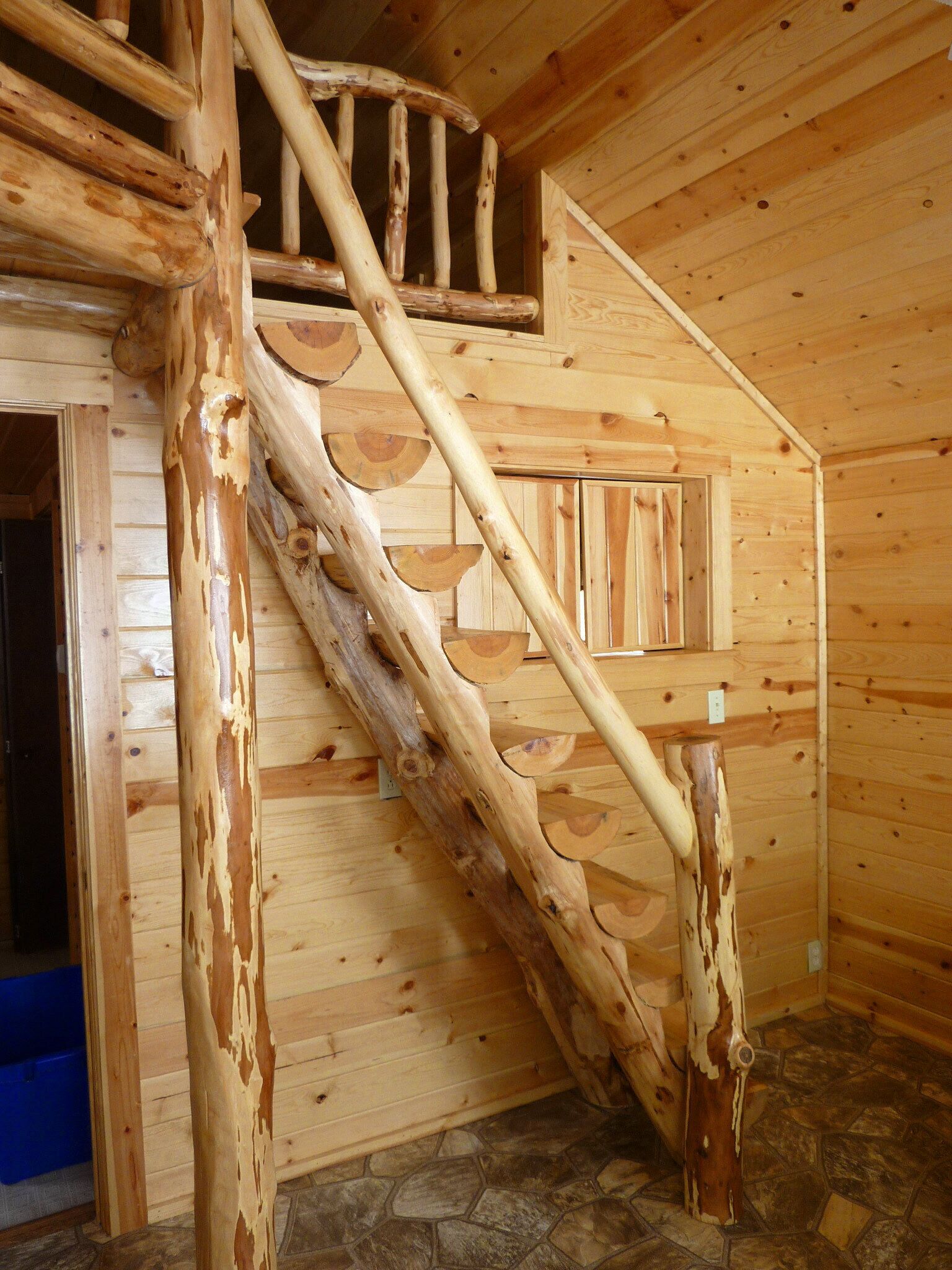 A wooden staircase with a unique design, leading to a second-floor area.