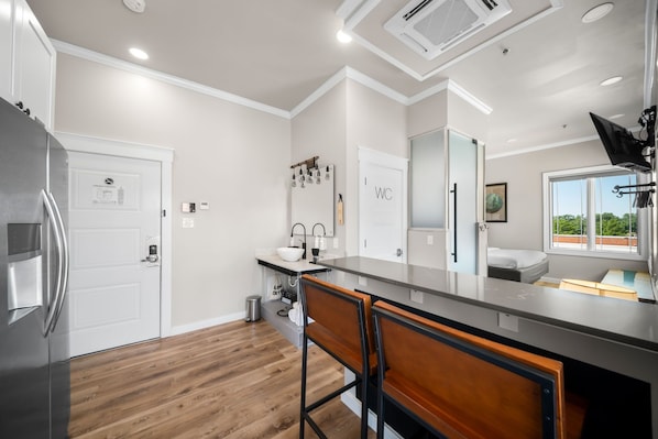 Una cocina moderna con un refrigerador de acero inoxidable, taburetes de bar de madera y un ventanal que ofrece vistas al exterior.
