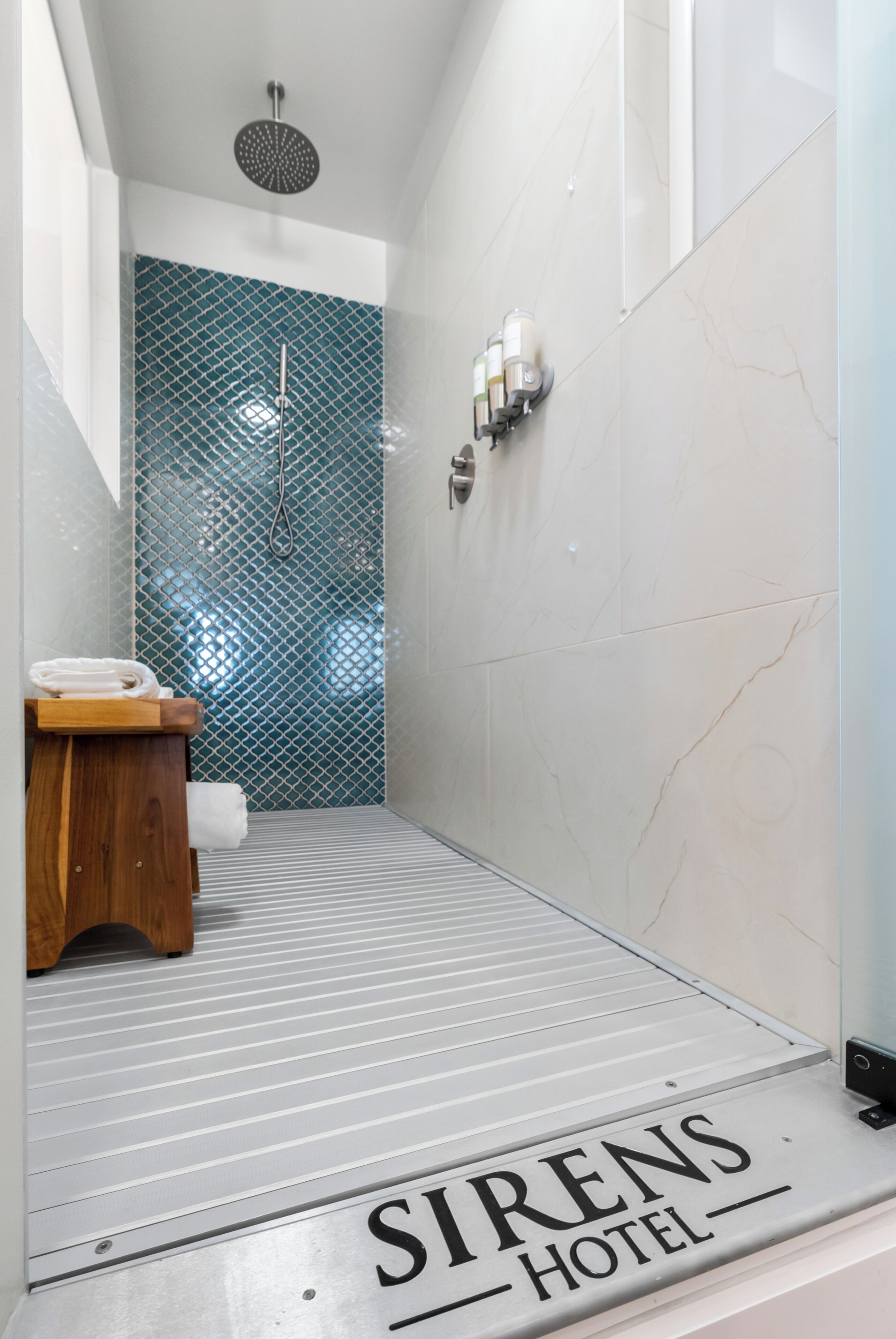 Un baño de hotel con ducha, un banco de madera y una toalla.