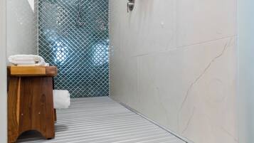 Un baño de hotel con ducha, un banco de madera y una toalla.