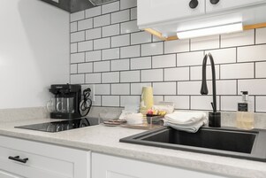 Una cocina moderna con un lavamanos negro, armarios blancos y un salpicadero de azulejos.
