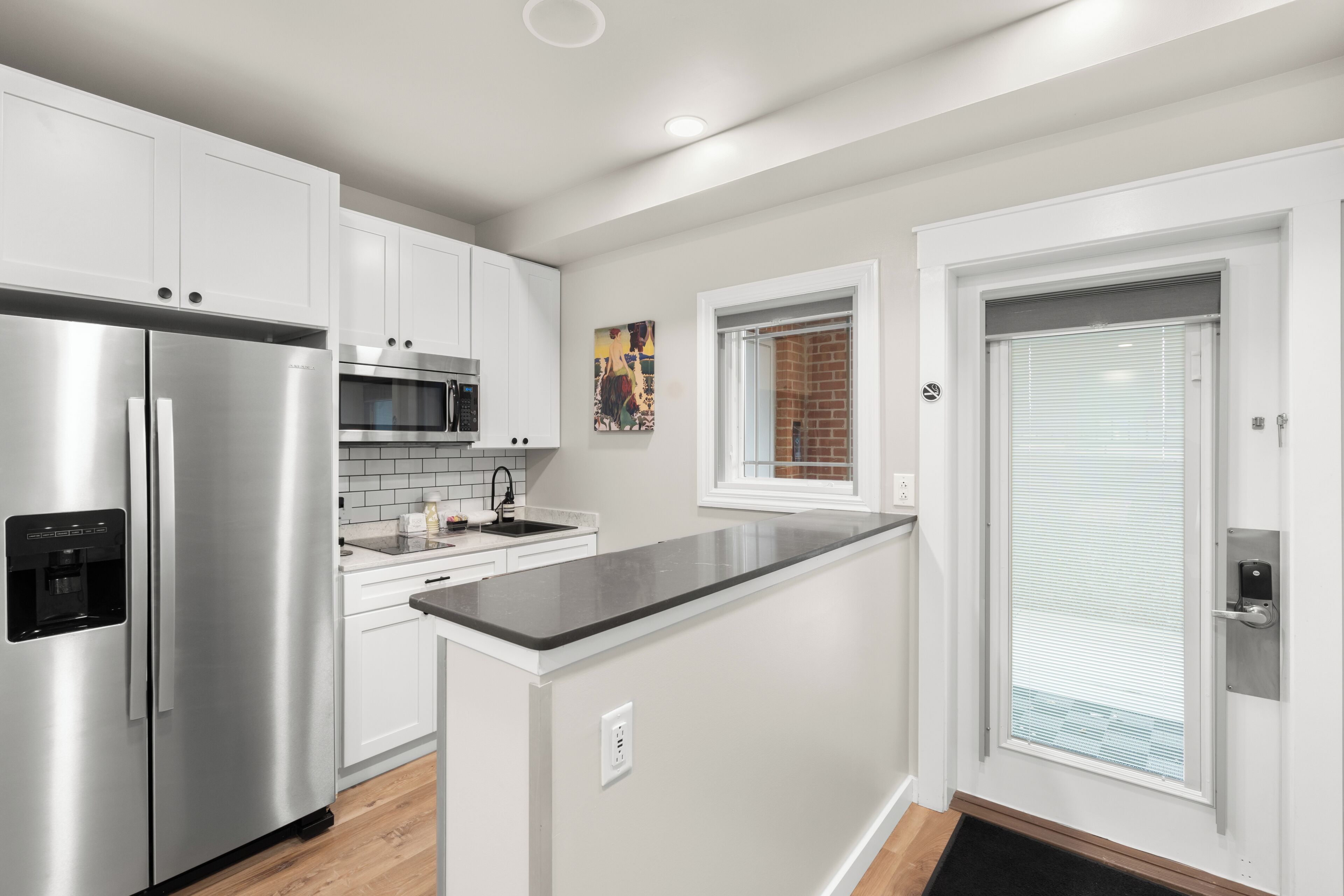 A modern kitchen with stainless steel appliances, white cabinetry, and a black countertop.