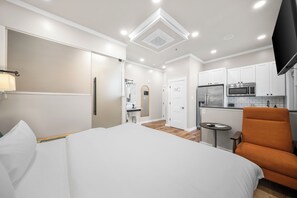 A hotel room with a bed, a desk, a chair, a kitchenette, and a bathroom. - River Sirens Hotel (Washington)