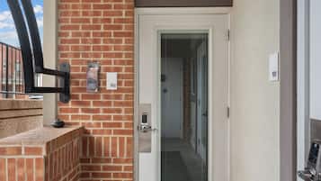 A door with a keypad lock, a brick wall, and a window with blinds.