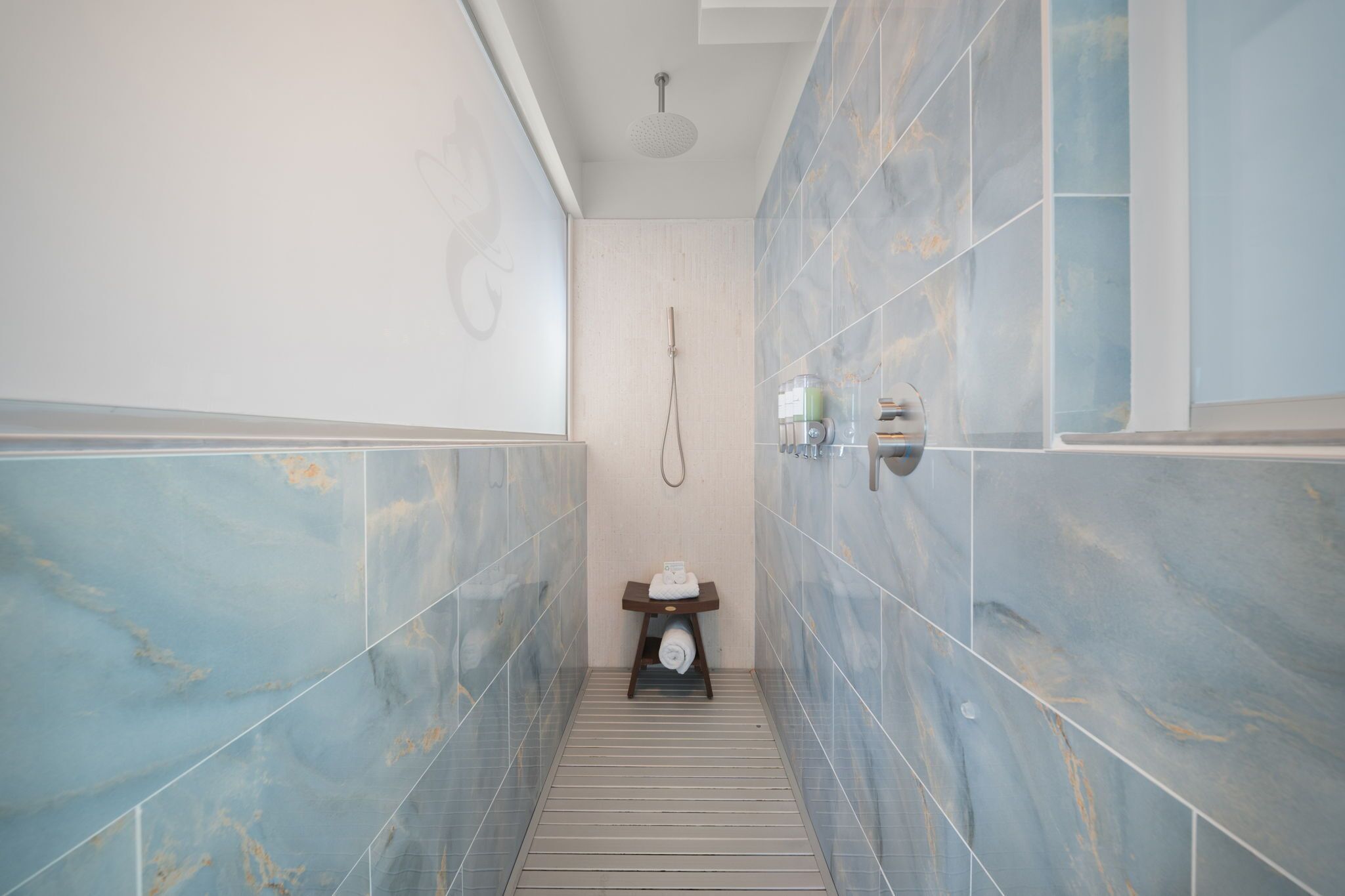 A bathroom with a shower, a towel rack, and a small table with a towel.