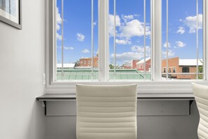 Una habitación con ventana que da a edificios, una silla y un radiador.