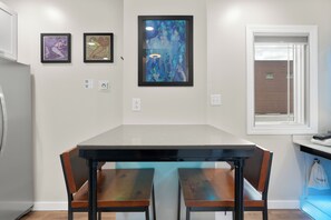 A modern kitchen with a large island, two chairs, and three framed artworks on the wall. - River Sirens Hotel (Washington)