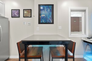 Una cocina moderna con una isla grande, dos sillas y tres cuadros en la pared.