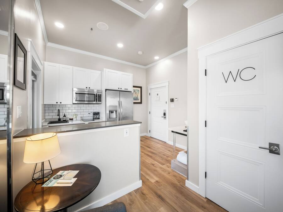 A modern kitchen with white cabinetry, stainless steel appliances, and a wooden floor.