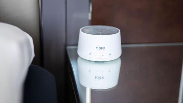 Een wit apparaat op een reflecterend oppervlak, mogelijk een oplaadstation of een speaker, met de merknaam 'pore' zichtbaar.