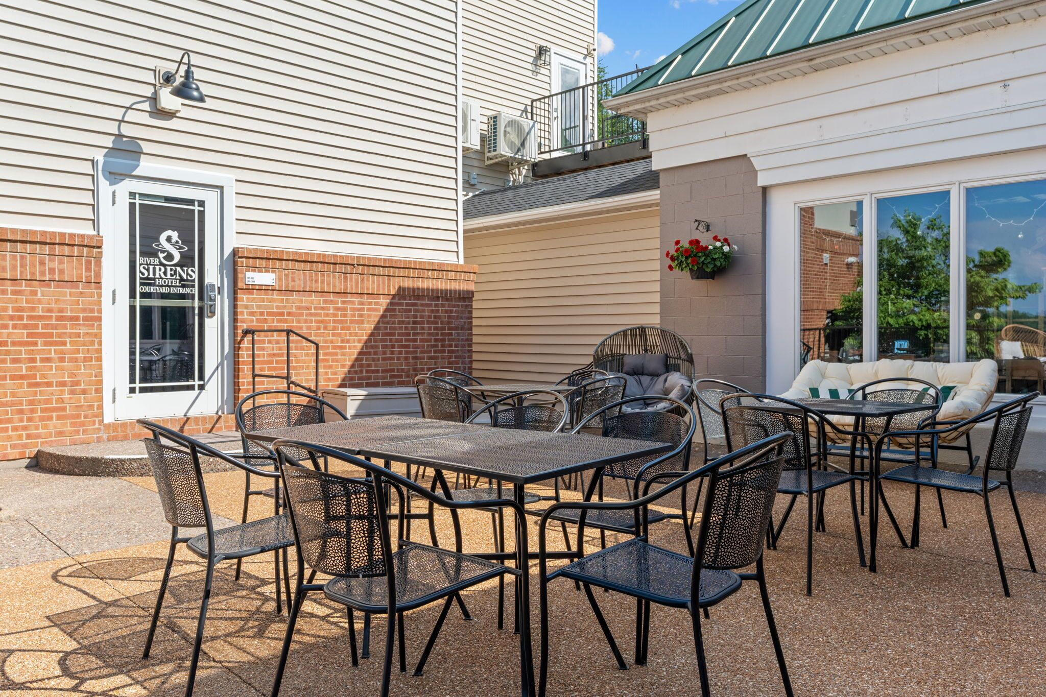 A River Sirens Hotel courtyard with outdoor seating and a brick wall.