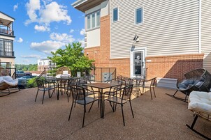 Un patio al aire libre con una mesa, sillas, un árbol y un edificio con un letrero.