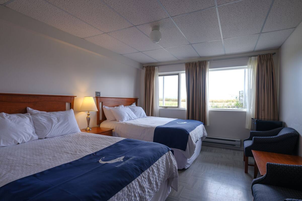 A hotel room with two beds, a desk, and a chair.